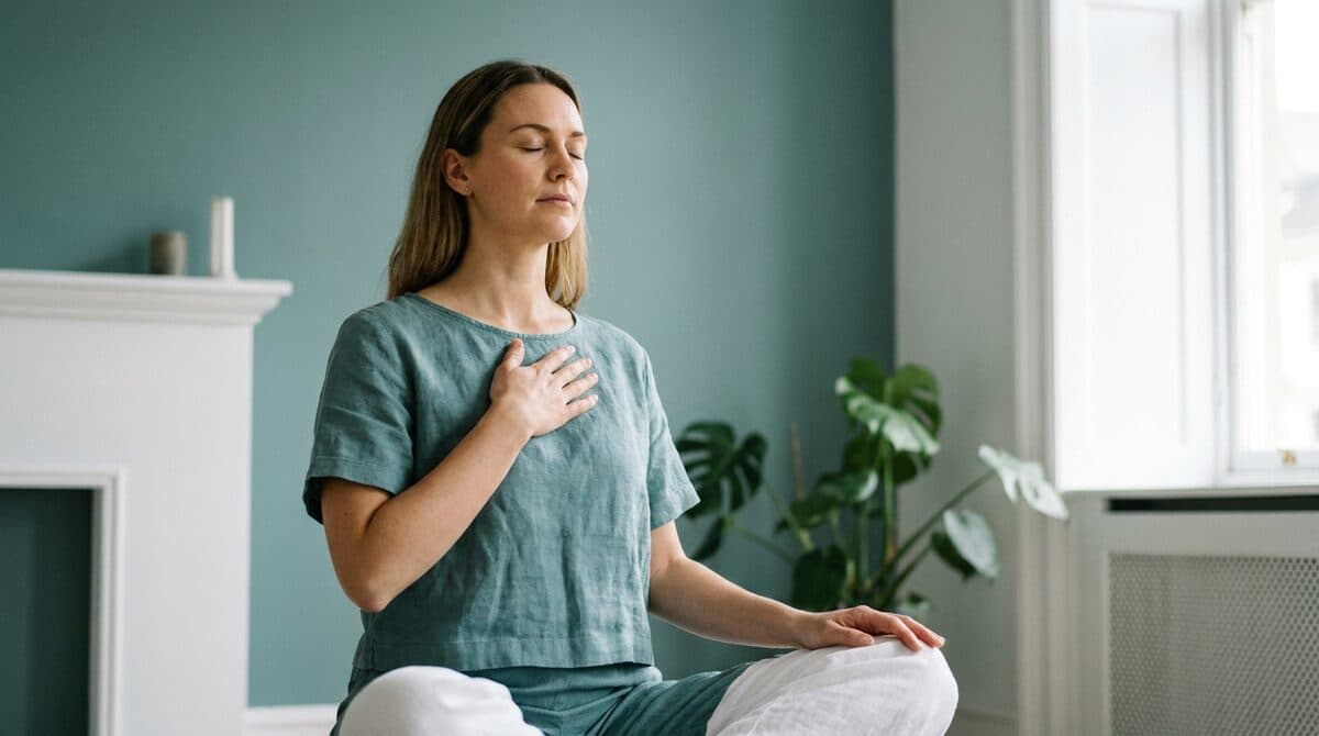 A person doing a calm breathing exercise with a hand on the chest — symbolizing relief of shortness of breath.